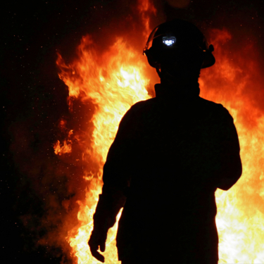 firefighter in front of flames by eliza giaccaglia (modified and cropped)